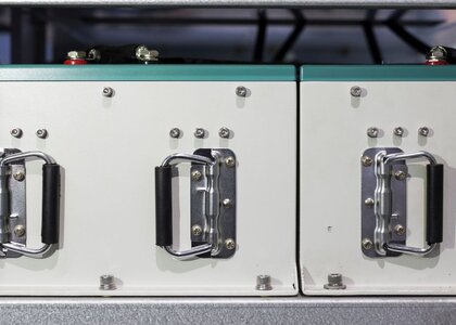 Image showing a of supercapacitor modules. A close up of the front of two supercapacitor modules. The modules are rectangular with each having two carrying handles and anode and cathode connections.