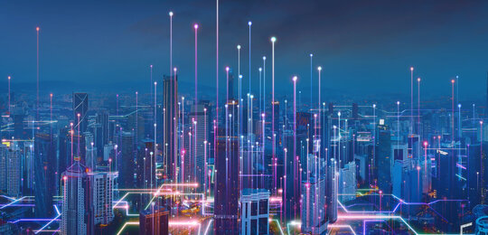 Artists impression of a “smart city” at night with vertical shafts of light rising from the buildings which are linked with glowing lines