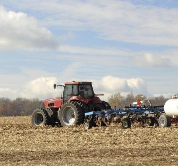 Image showing a tractor plowing and fertilising a field