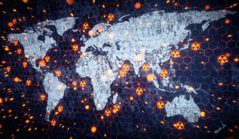 A stylised image of the world with the continents in white and the oceans in deep blue. Dotted around the land and oceans are nuclear hazard symbols representing nuclear explosions or tests