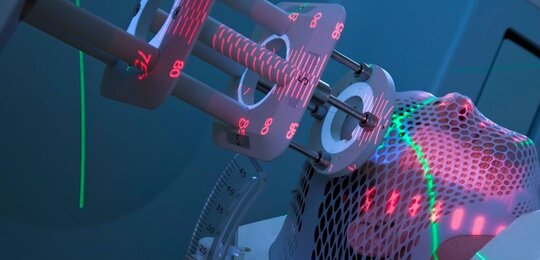 Close up of a man’s head wrapped in protective gauze with the head of a radiation delivery instrument pressed to his temple