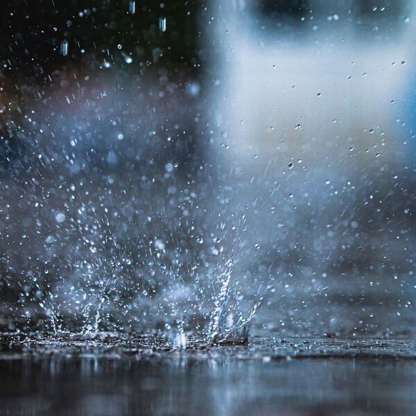 Image showing rain falling into a puddle, causing a splash of water