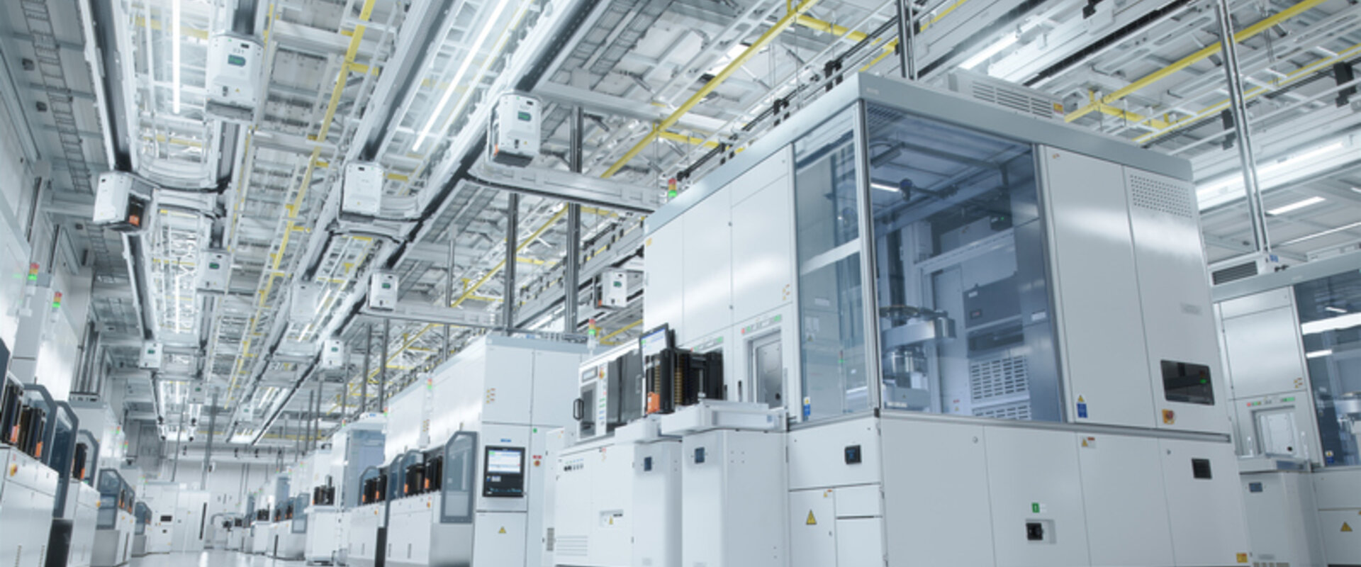 In a grey and sterile warehouse a series of enclosed modules producing semiconductors stretch off into the distance