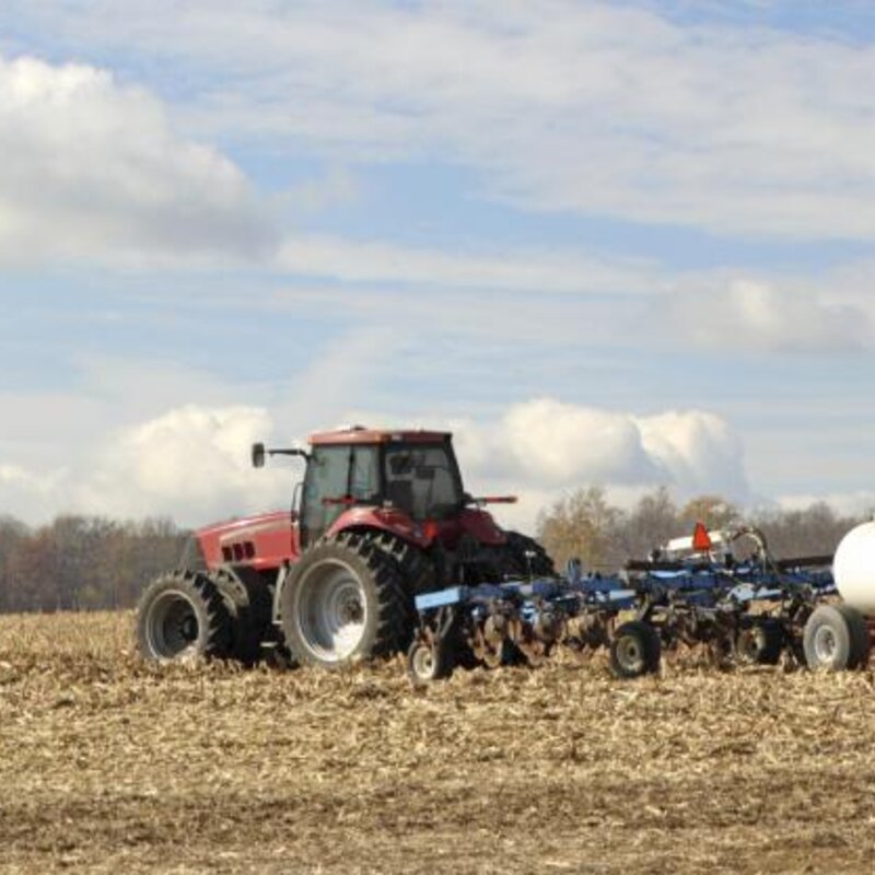 Image showing a tractor plowing and fertilising a field
